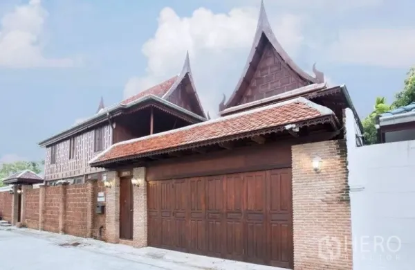 บ้าน ให้เช่าในBang Na, Bangkok - ด้านหน้าบ้านและประตูไม้บานใหญ่ กำแพงอิฐ และหลังคาจั่วไทย