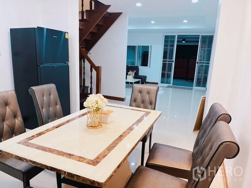 Townhouse for rent in Huai Khwang, Bangkok - Dining area beside the staircase with a large fridge, looking toward the living room.