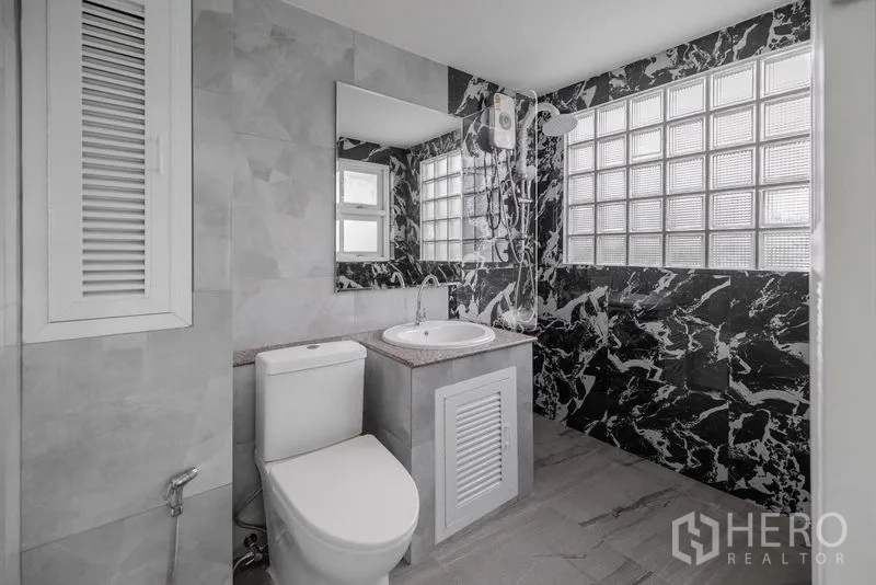 Townhouse for sale - Contemporary bathroom with glass-block shower wall and striking black patterned tiles.