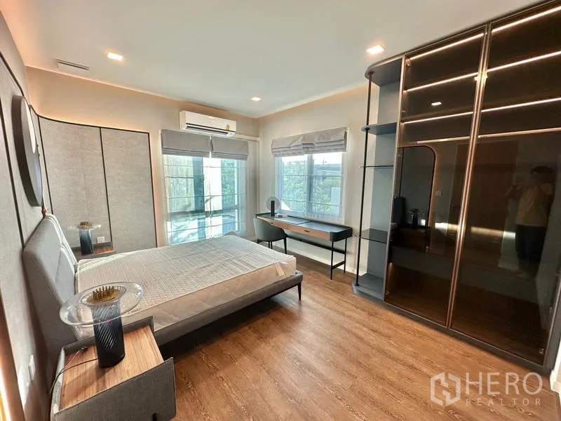 Detached House for rent in Samut Prakan - Guest bedroom with large windows, built-in glass wardrobe and a writing desk.