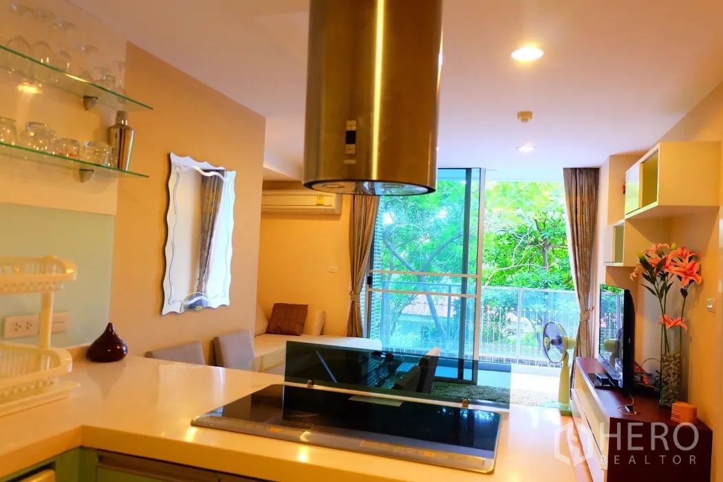 公寓 出租在Phaya Thai, Bangkok - 从厨房望向客厅与阳台，推拉落地门外是绿意景观。