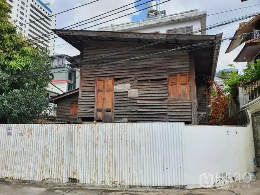 独立式住宅 出租在Sathon, Bangkok - 城市街景中的老木屋，白色波纹铁皮围墙。