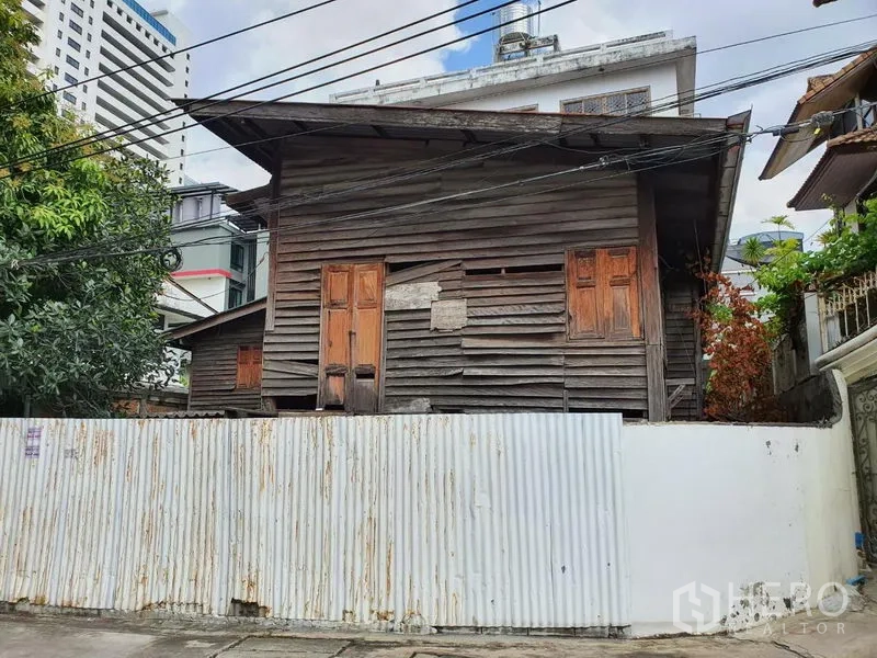 独立式住宅 出租在Sathon, Bangkok - 城市街景中的老木屋，白色波纹铁皮围墙。