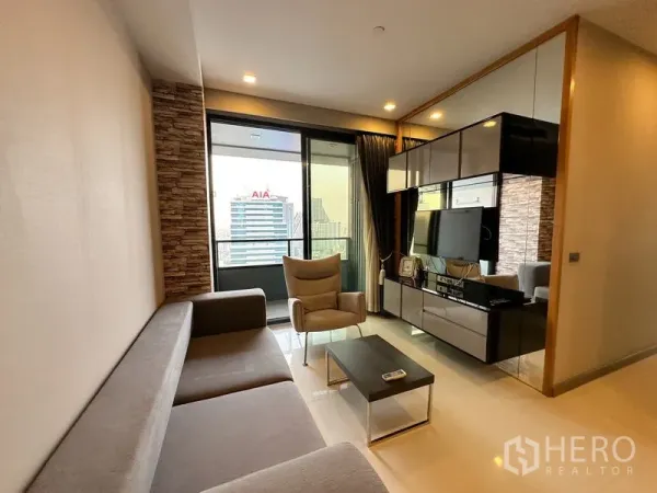 公寓 出租在Bang Rak, Bangkok - 明亮客厅，沙发与电视柜，落地窗连通阳台，俯瞰曼谷天际线