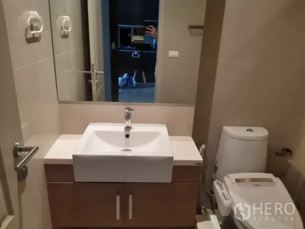 公寓 出租在Bangkok - 紧凑卫浴，设大镜面、台上盆与现代坐便器。