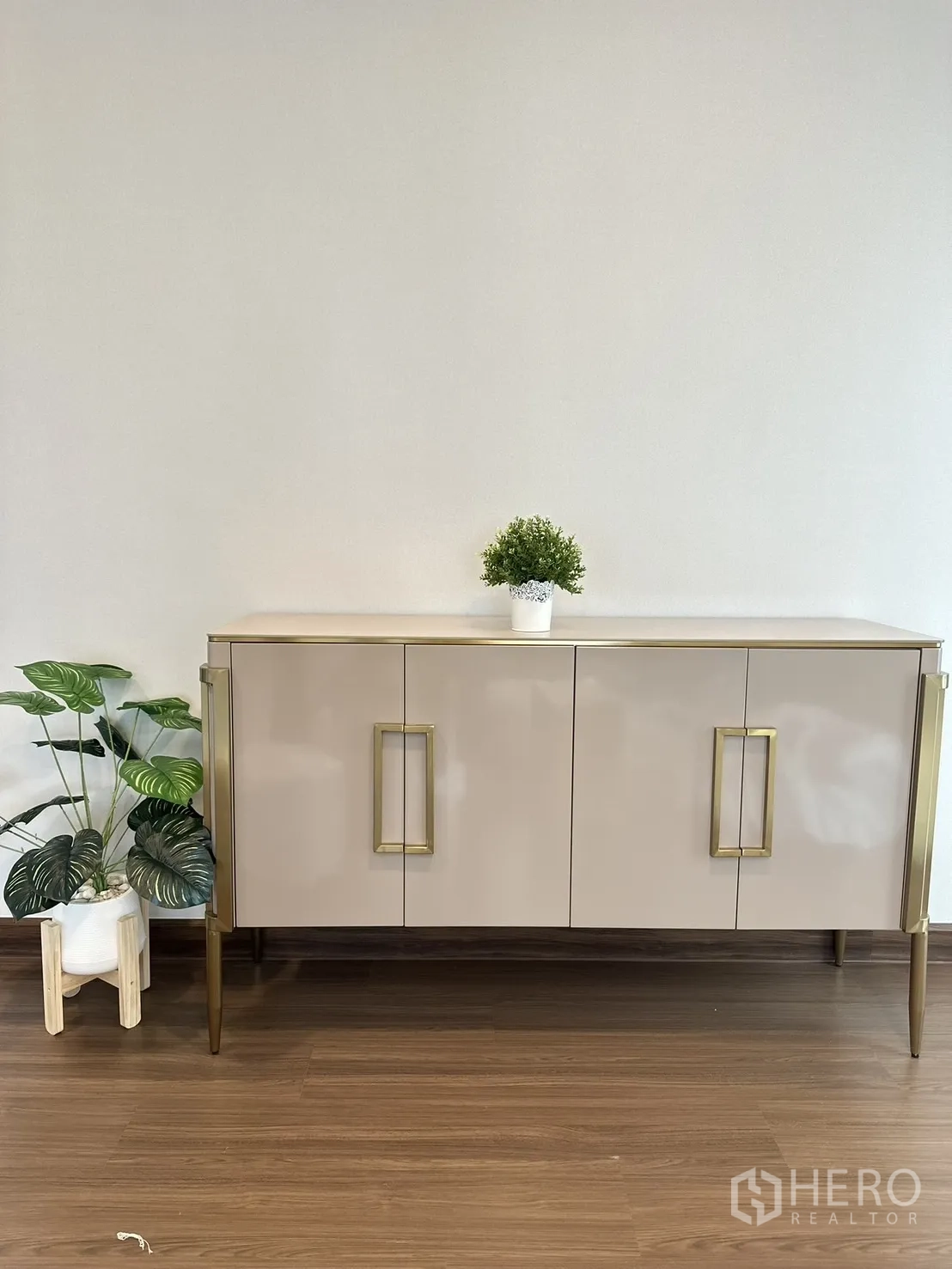 Detached House for rent or sale - Minimal console cabinet with gold handles and potted plants against plain wall.