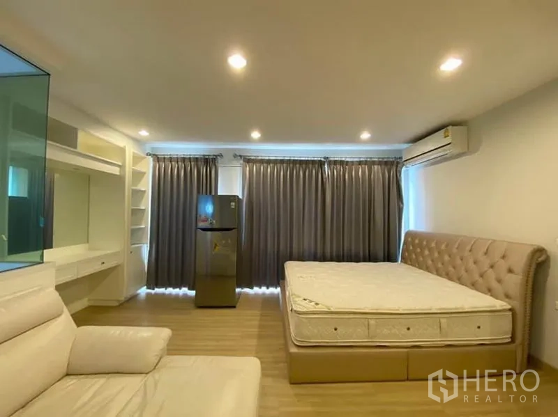 Townhouse for rent in Bang Na, Bangkok - Spacious bedroom with upholstered bed, built‑ins, air conditioner, and dark curtains.