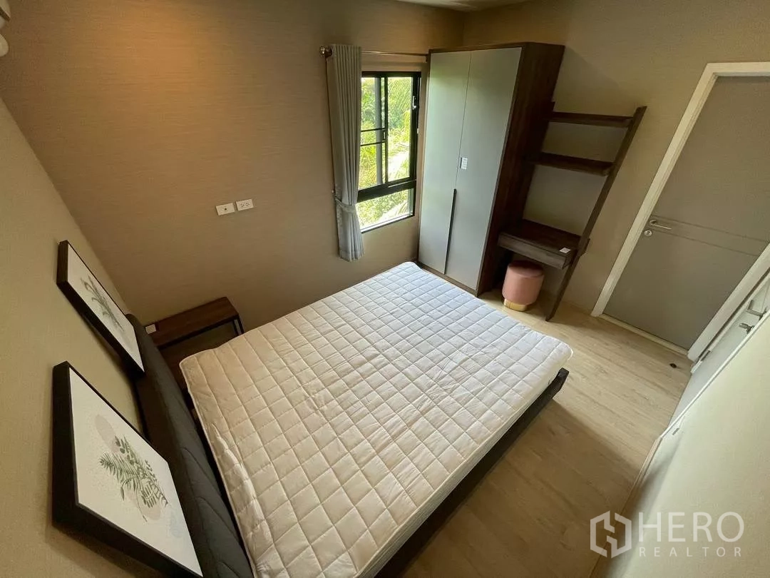 Townhouse for rent in Suan Luang, Bangkok - Cozy bedroom with queen bed, wardrobe, corner desk and sunlight from a side window.