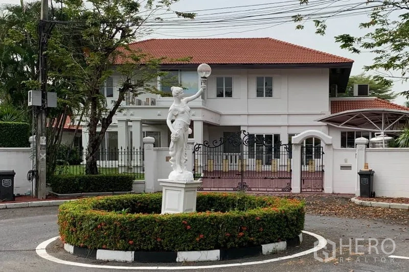 Detached House for rent in Bang Phli, Samut Prakan - Front view of the home from a landscaped roundabout with a classical statue and gated entrance.