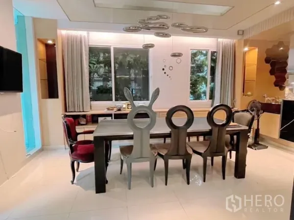独立式住宅 出租或出售在Prawet, Bangkok - 餐厅设长桌、设计师餐椅与造型吊灯，临窗而设。