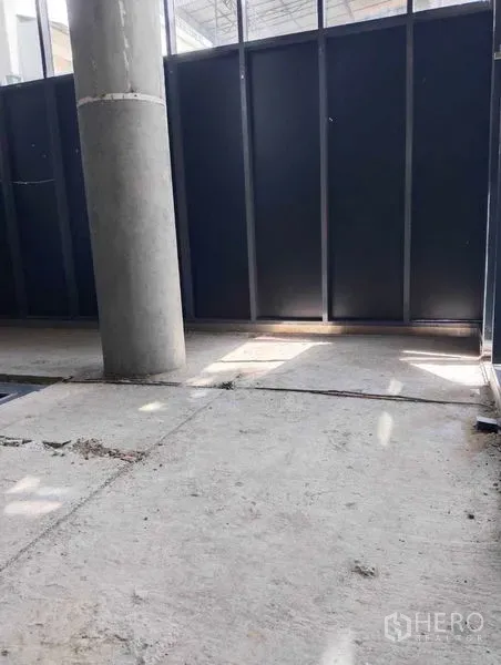 Retail Space for rent in Watthana, Bangkok - Ground-level entrance area with concrete column, metal screen panels and raw slab flooring.