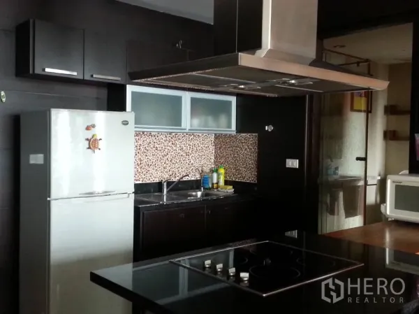 Condominium for rent in Khlong San, Bangkok - Full kitchen with dark cabinets, mosaic backsplash, stainless range hood and electric cooktop.