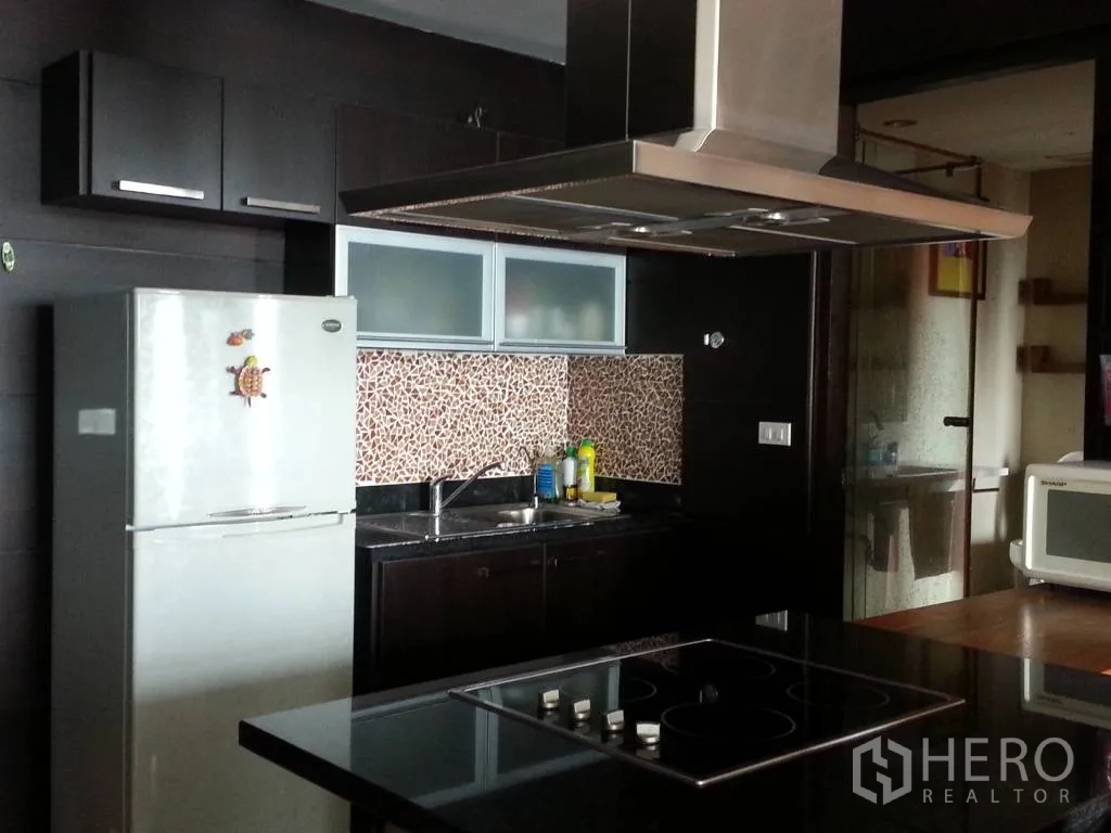 Condominium for rent in Khlong San, Bangkok - Full kitchen with dark cabinets, mosaic backsplash, stainless range hood and electric cooktop.
