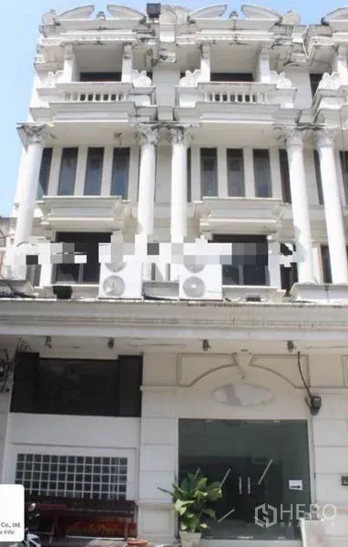 Shophouse for rent in Khlong Toei, Bangkok - Neoclassical white shophouse facade with columns and a glass shopfront in Bangkok near BTS Ekkamai.