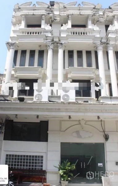 Shophouse for rent in Khlong Toei, Bangkok - Neoclassical white shophouse facade with columns and a glass shopfront in Bangkok near BTS Ekkamai.