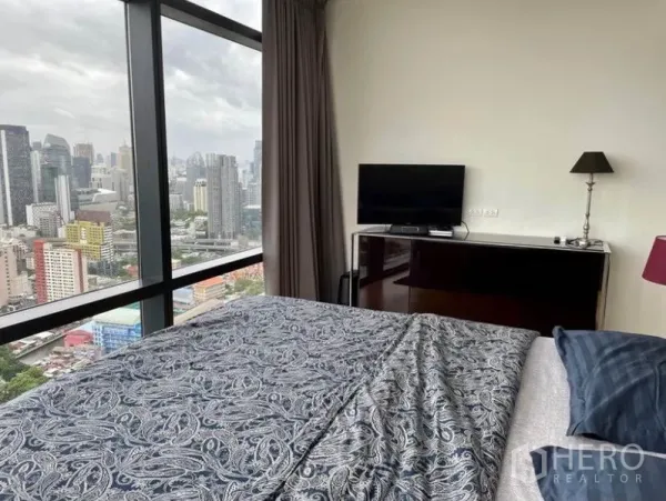 Condominium for sale in Ratchathewi, Bangkok - Bedroom with TV cabinet and full-height window overlooking the city.