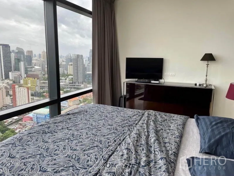 Condominium for sale in Ratchathewi, Bangkok - Bedroom with TV cabinet and full-height window overlooking the city.