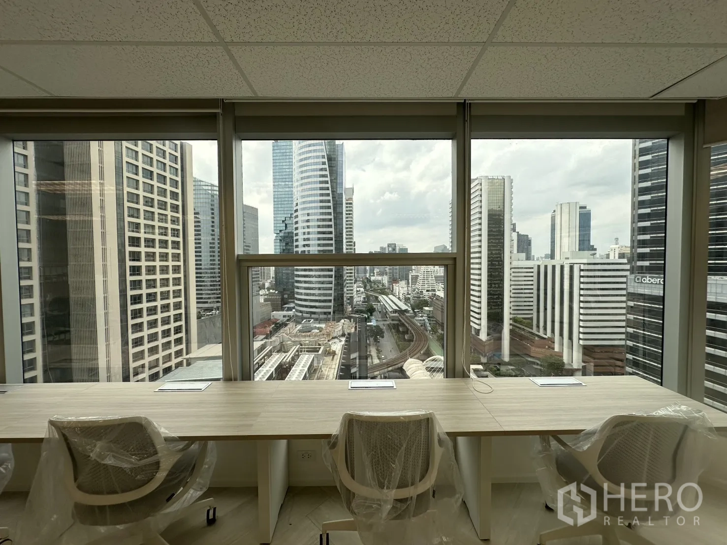 办公室 for rent in Sathon, Bangkok - 从窗边工位望向城市，高楼与轨道线尽收眼底。