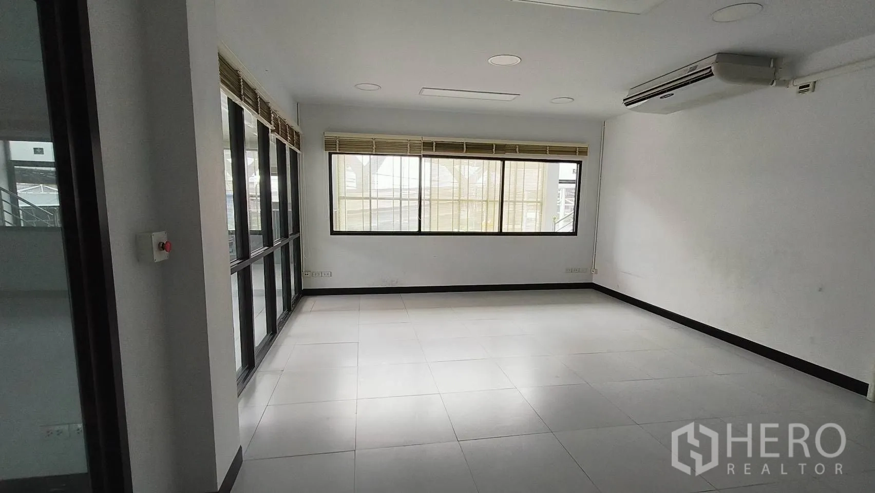 办公空间 出租在Khlong Toei, Bangkok - 转角办公室，玻璃墙与百叶，俯瞰大厅。