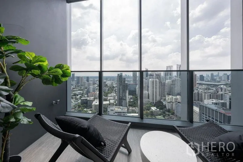 Condominium for rent in Khlong Toei, Bangkok - High-rise balcony lounge with potted plant and panoramic skyline view across Sukhumvit.