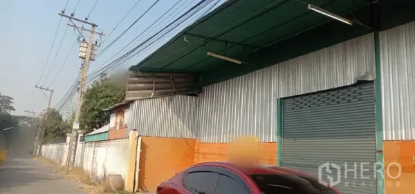 Warehouse for rent in Bueng Kum, Bangkok - Street-side warehouse exterior with corrugated metal cladding, green awning and a large roll-up door in Bueng Kum, Bangkok.