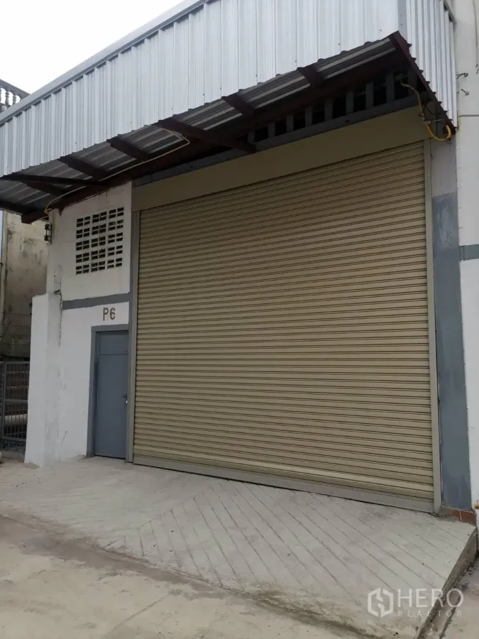 Warehouse for rent in Suan Luang, Bangkok - Warehouse exterior in Suan Luang, Bangkok with large roller shutter door, steel awning and side access door.
