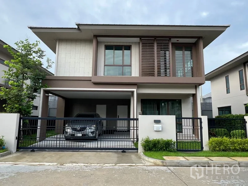 Detached House for rent in Bang Kapi, Bangkok - Front elevation of the detached house with black gate, small garden and carport.