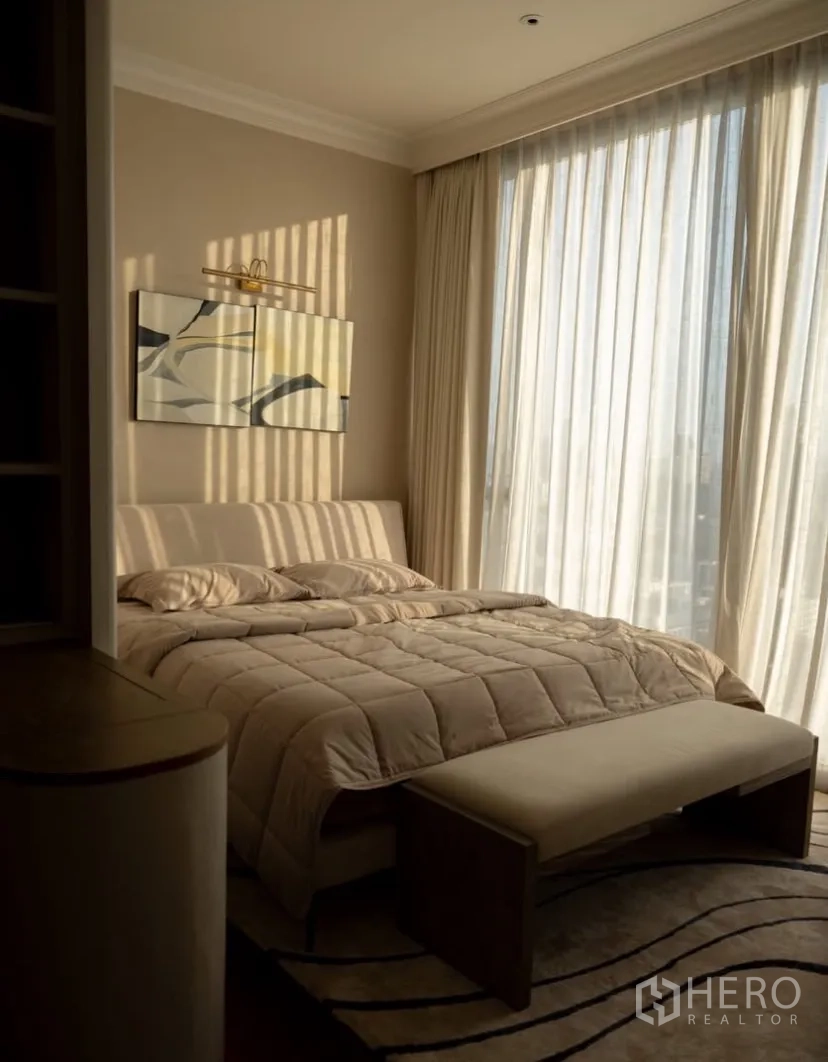 Condominium for rent or sale in Watthana, Bangkok - Cozy bedroom with neutral bedding and floor-to-ceiling drapes.