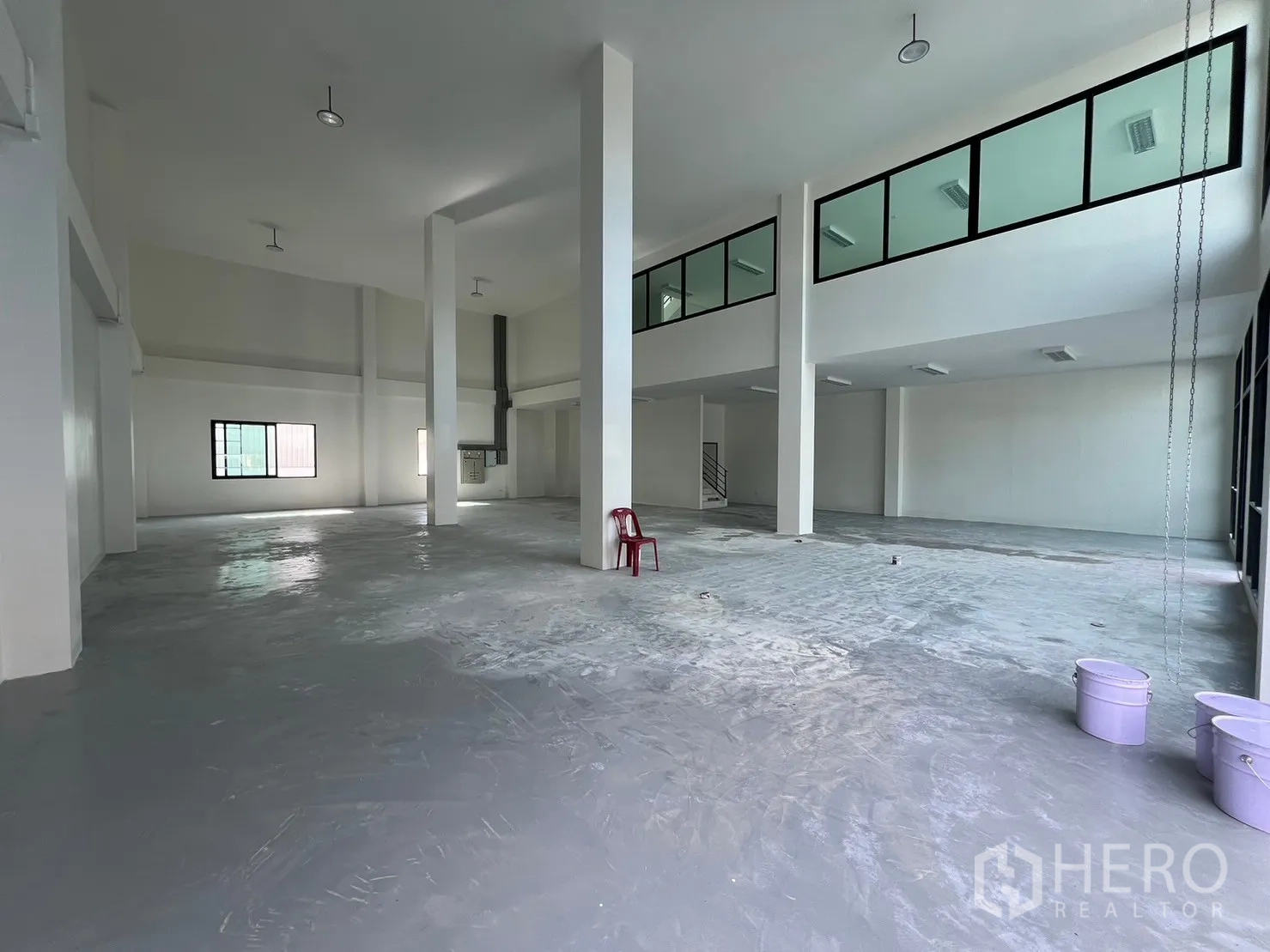 Warehouse for rent in Samut Prakan - Spacious warehouse hall with columns, mezzanine offices and durable epoxy concrete flooring.