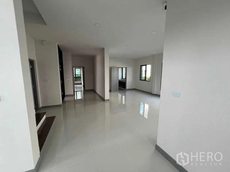 独立式住宅 出租在Khlong Sam Wa, Bangkok - 一层开放式空间，白色地砖，多扇窗，连通厨房。