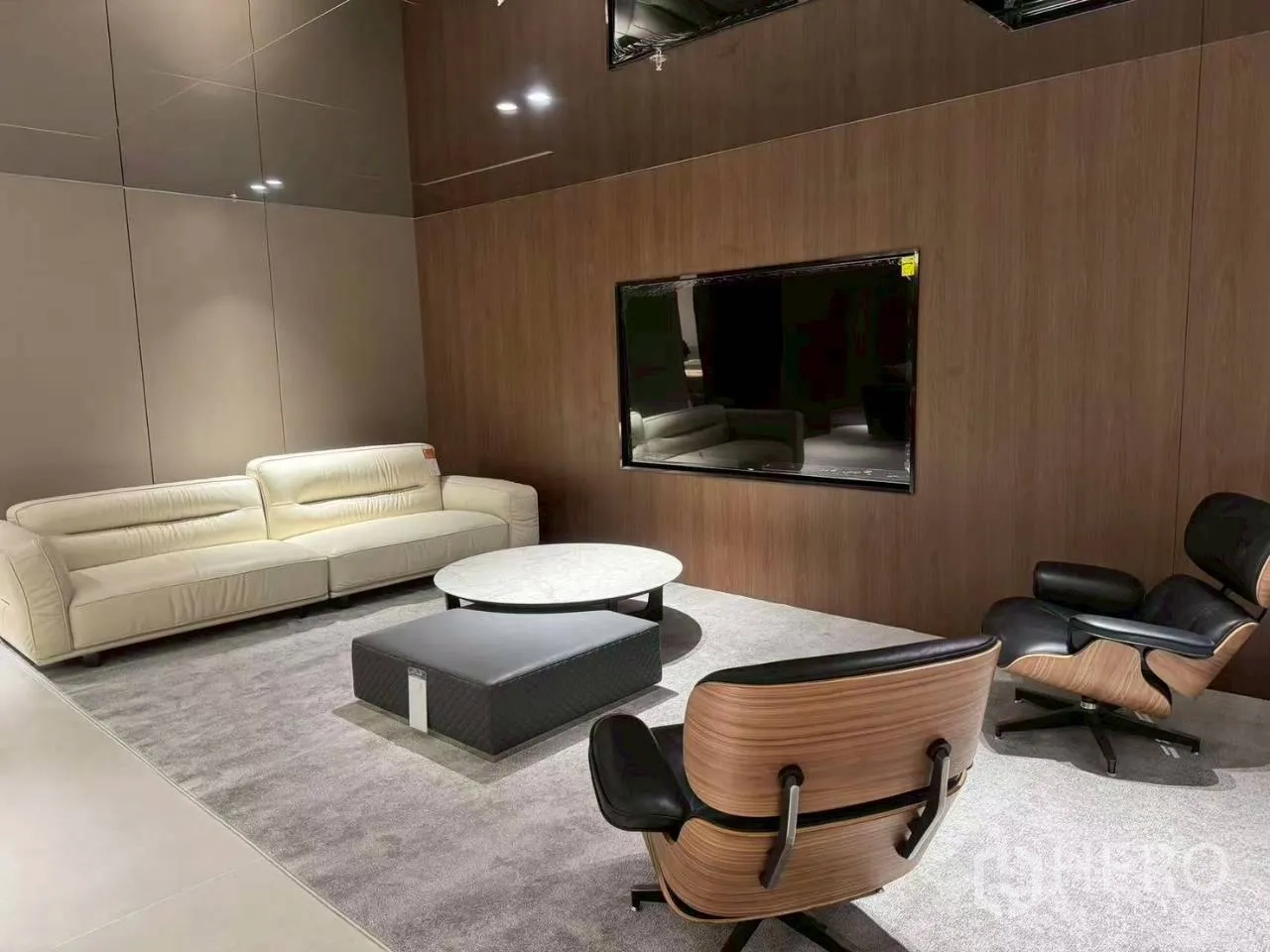Office Space for rent in Din Daeng, Bangkok - Private media lounge with cream sofa, Eames-style chair, wood wall panels, and a wall-mounted screen.