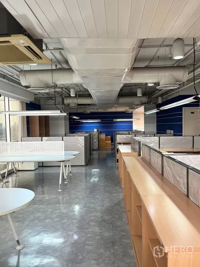 Office Space for rent in Khlong Toei, Bangkok - Open-plan office floor with cubicles, round tables, shelving and industrial ceiling ducts.