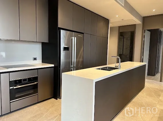 คอนโด for rent in Watthana, Bangkok - ห้องครัวสไตล์โมเดิร์นพร้อมไอแลนด์ เตาและเตาอบบิวท์อิน ตู้สูง และตู้เย็นสแตนเลสประตูคู่