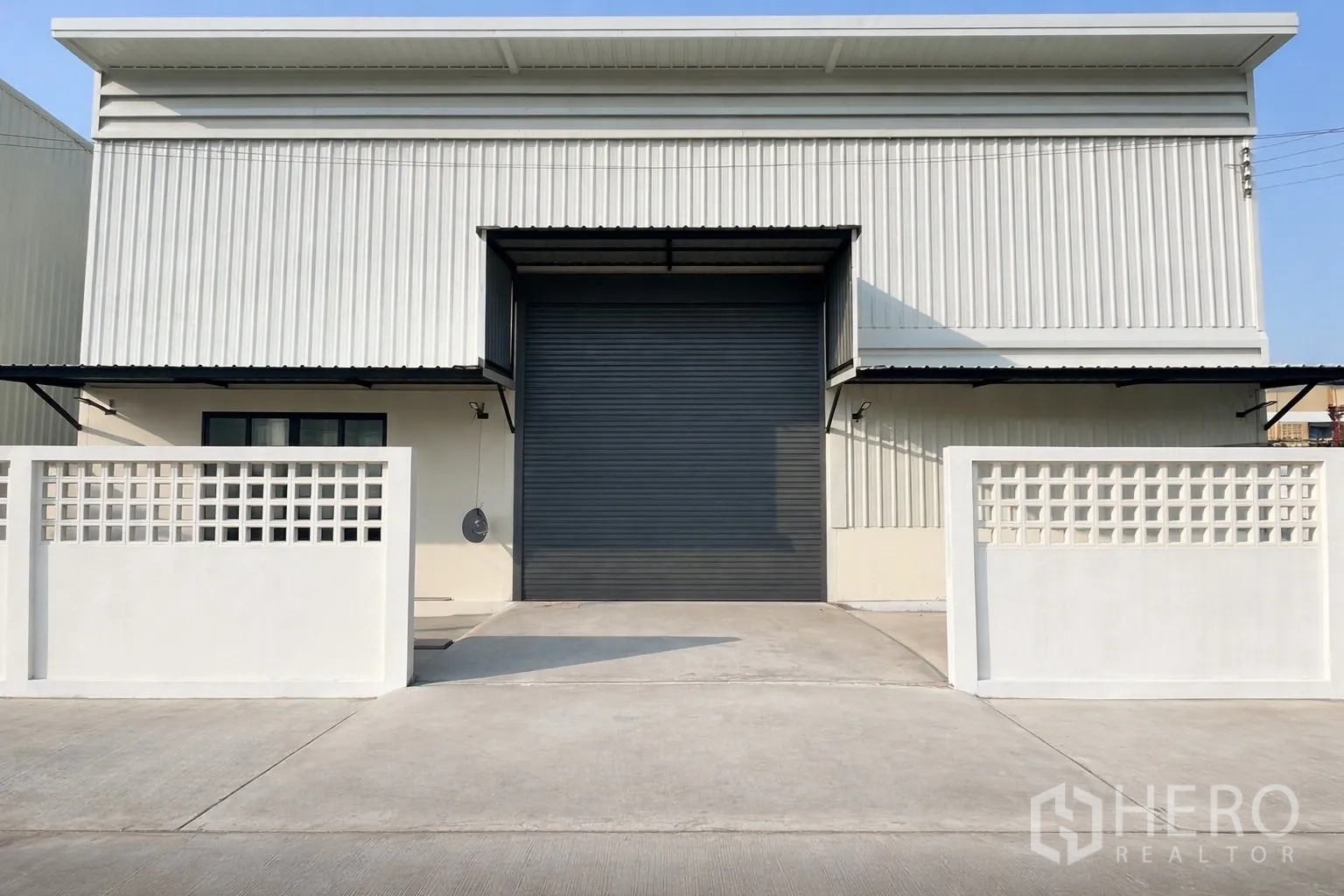 Warehouse for rent in Prawet, Bangkok - Front exterior of the warehouse with gated driveway and large roller shutter.