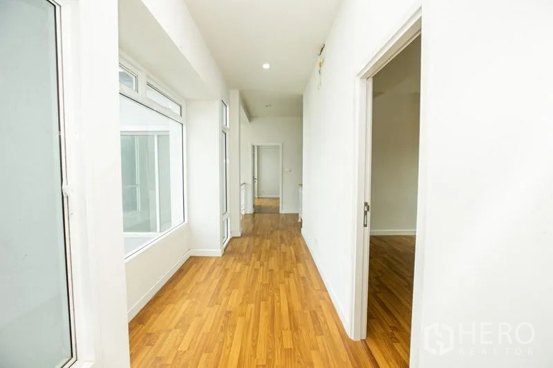 Detached House for rent or sale in Lam Luk Ka, Pathum Thani - Wide front view of the property with driveway, gate and landscaped hedge.