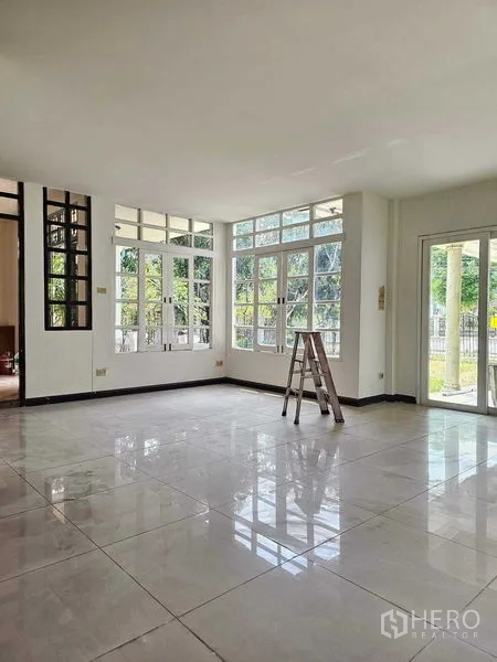 Detached House for sale in Saphan Sung, Bangkok - Bright open-plan living area with glossy tiled floors and wraparound windows opening to the garden.
