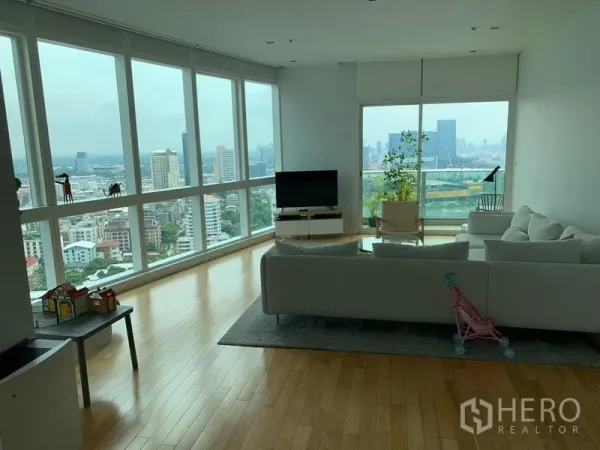 公寓 出租在Khlong Toei, Bangkok - 转角客厅配落地窗与浅色木地板，俯瞰曼谷天际线