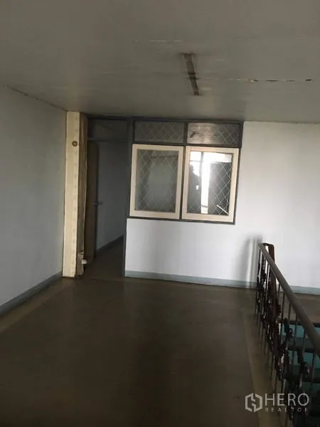 Shophouse for rent in Phra Khanong, Bangkok - Upper-floor landing with windowed partition beside the stair railing.