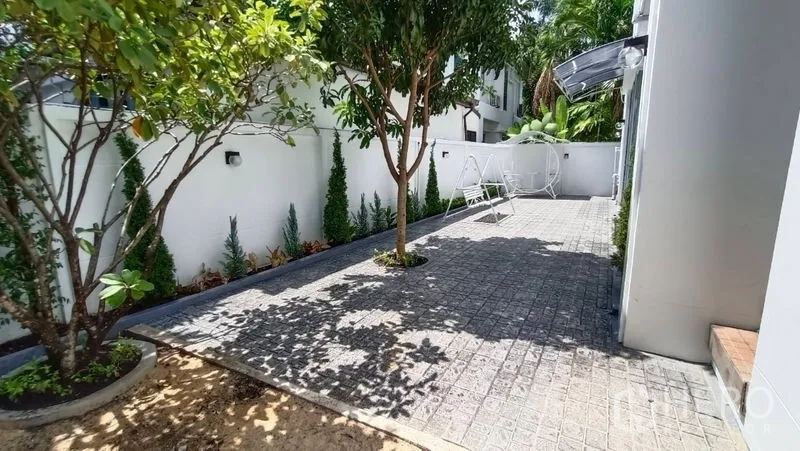独立式住宅 出租在Prawet, Bangkok - 铺砖庭院，中间有树，白色围墙与花园秋千