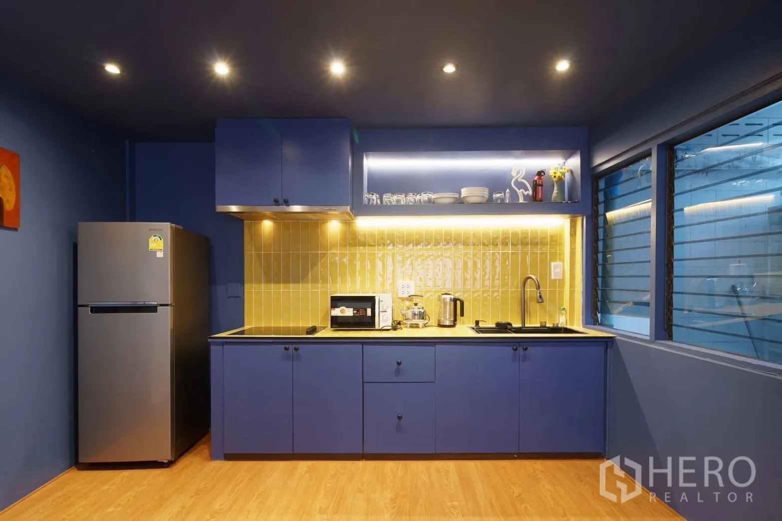 ทาวน์เฮาส์ for rent in Watthana, Bangkok - ครัวสีน้ำเงินสมัยใหม่ ผนังหลังเตาโทนเหลือง พร้อมเตา เครื่องดูดควัน ตู้เย็น และไมโครเวฟ