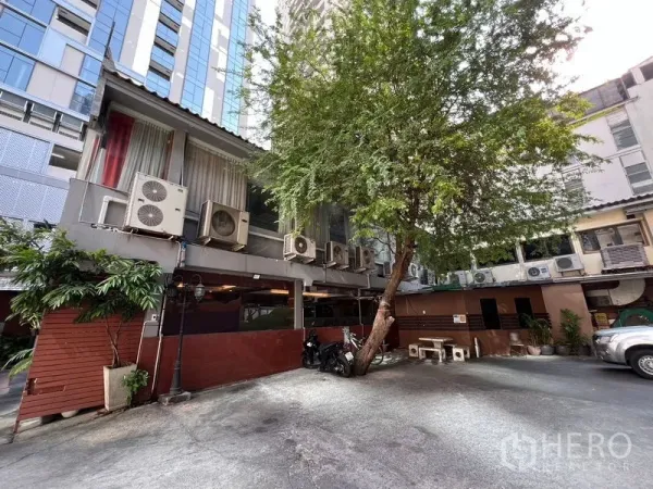 Retail Space for rent or sale in Khlong Toei, Bangkok - Courtyard of the retail property with mature tree, parking space and exterior air-conditioning units in Khlong Toei, Bangkok.