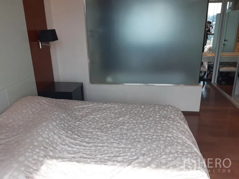 Condominium for rent in Khlong Toei, Bangkok - Bedroom with queen bed and a frosted glass partition.