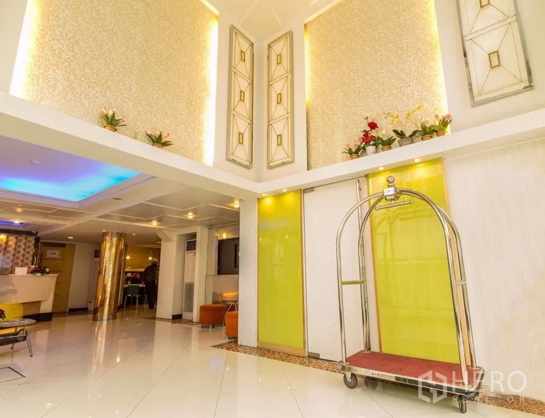 Retail Space for rent - Double-height lobby with decorative wall panels and a luggage cart near sliding doors.