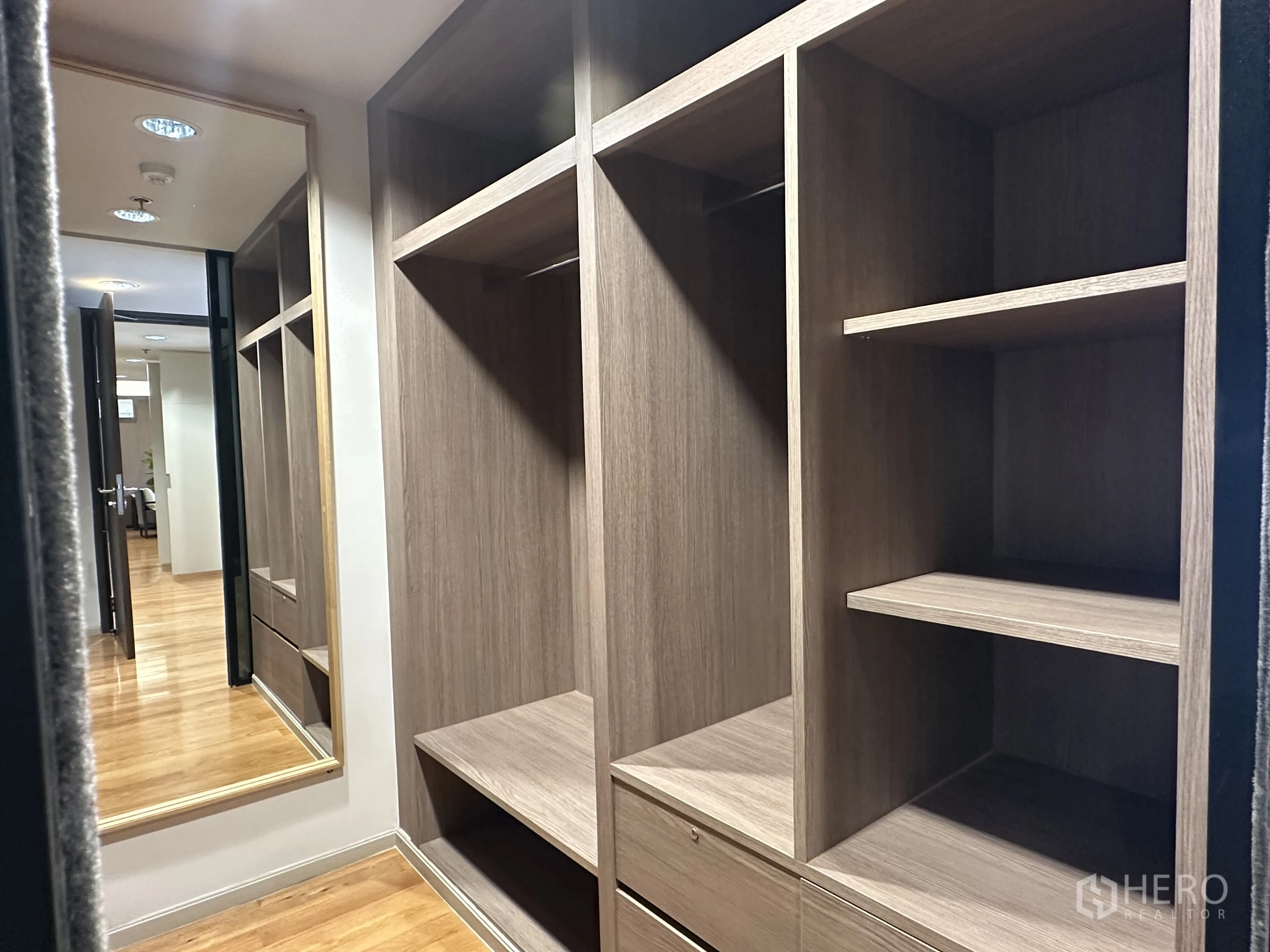 Condominium for rent in Khlong Toei, Bangkok - Walk-in closet with custom wood shelving and a full-height mirror.
