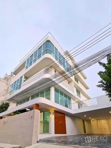 带办公室的家 出售在Suan Luang, Bangkok - 白天转角外观，圆角玻璃与车道入口