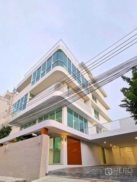 带办公室的家 出售在Suan Luang, Bangkok - 白天转角外观，圆角玻璃与车道入口