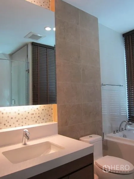 Condominium for rent in Khlong Toei, Bangkok - Vanity area with illuminated mirror, countertop sink and view toward the bathtub.