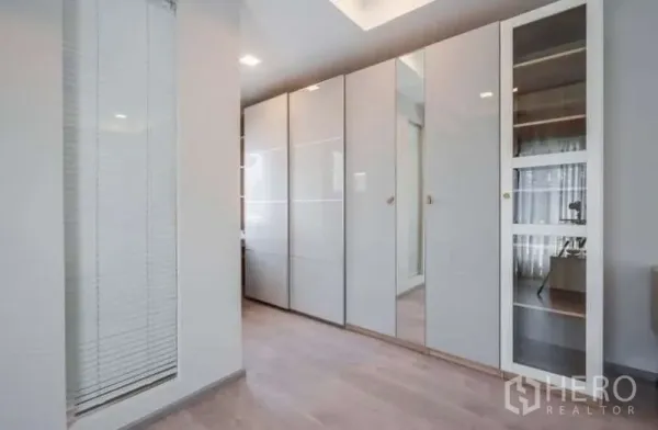 独立式住宅 出租在Prawet, Bangkok - 步入式衣柜走廊，通顶高光衣柜与浅木地板。