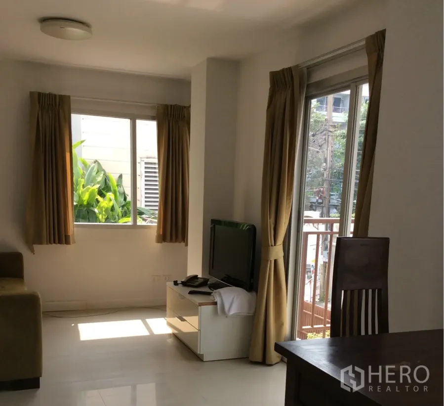 公寓 出售在Pathum Wan, Bangkok - 明亮客厅，带电视柜、沙发及米色窗帘的阳台门，曼谷巴吞旺公寓。