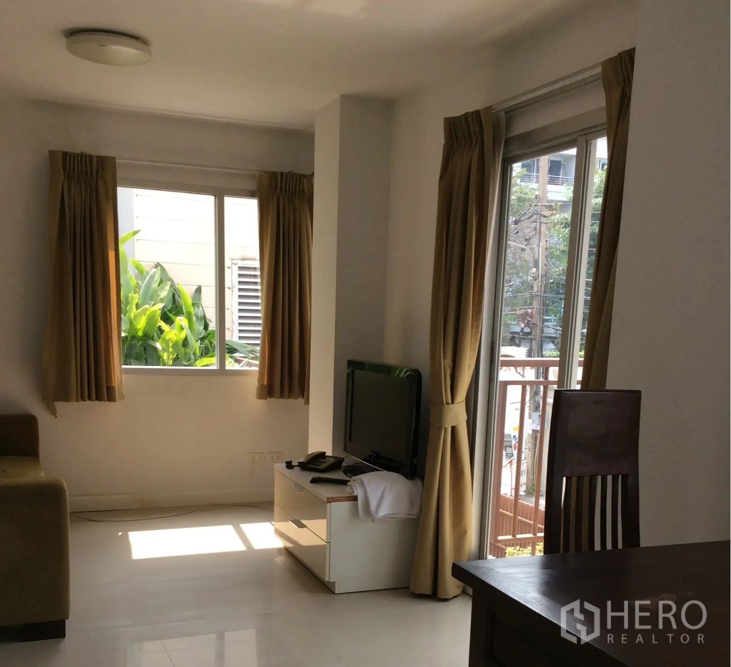 公寓 出售在Pathum Wan, Bangkok - 明亮客厅，带电视柜、沙发及米色窗帘的阳台门，曼谷巴吞旺公寓。